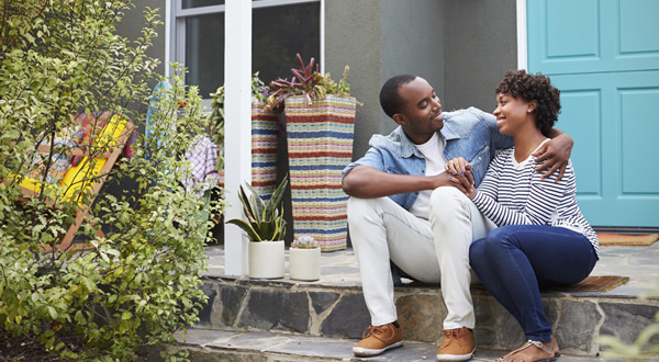 couple sitting in front of house